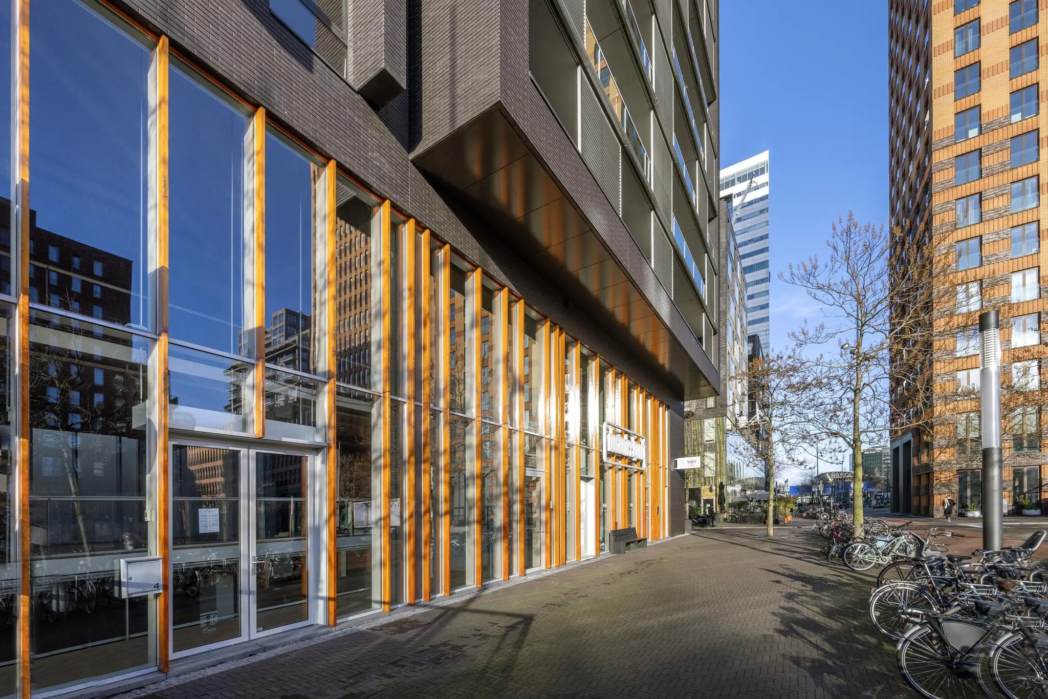 Moderne hoogbouw en glazen gevels aan het George Gershwinplein in Amsterdam met geparkeerde fietsen op de voorgrond.